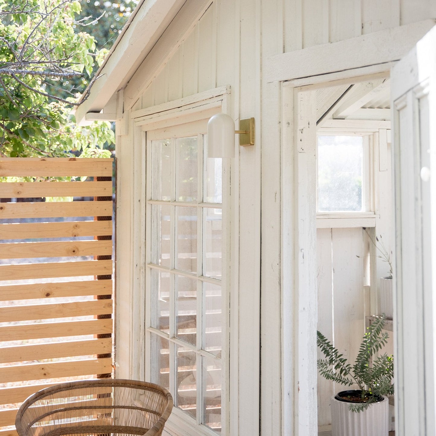 White Allegheny 4.5-inch sconce mounted on a white siding wall beside a glass‑paned door on a sunlit porch