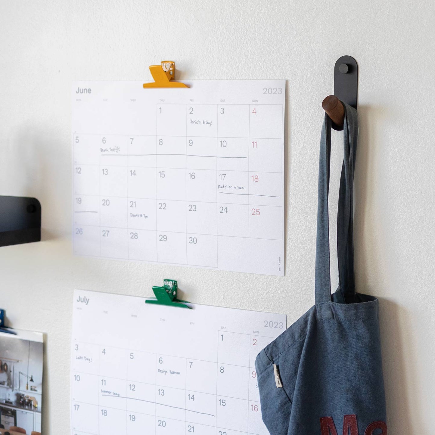 Side view of Perkins Single Hook showcasing angled wooden peg and black powder coated steel on white wall with hanging bag
