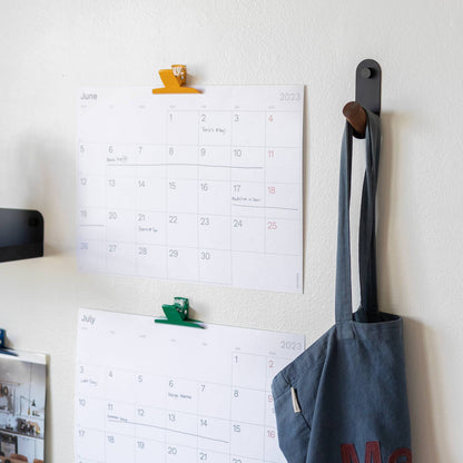 Side view of Perkins Single Hook showcasing angled wooden peg and black powder coated steel on white wall with hanging bag