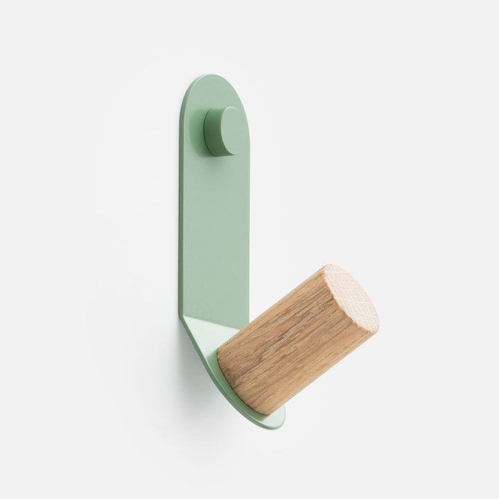 Angled view of Perkins Single Hook showing hardwood peg and laurel green powder coated steel on white background