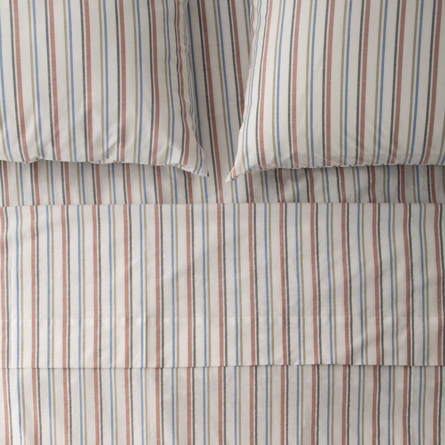 Top-down view of Fresh Stripe percale sheeting showcasing narrow blue and rust vertical stripes with two pillowcases on a flat bed