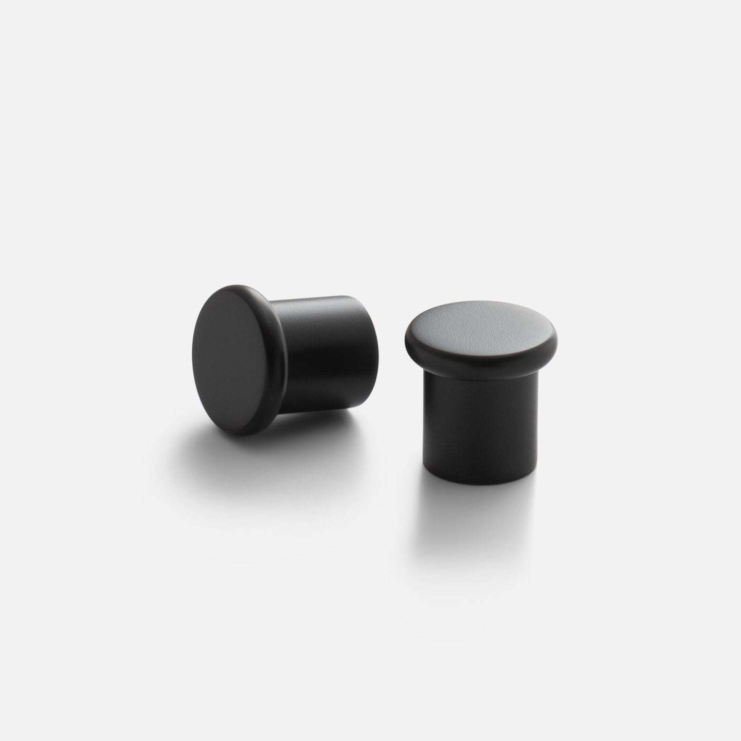 Three-quarter view of Remy Knob showing soft curved top and short cylindrical stem in matte black finish on white background
