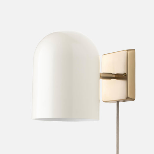 Side view of Allegheny 6” plug-in sconce with white dome shade, satin brass backplate, and fabric cord on gray background