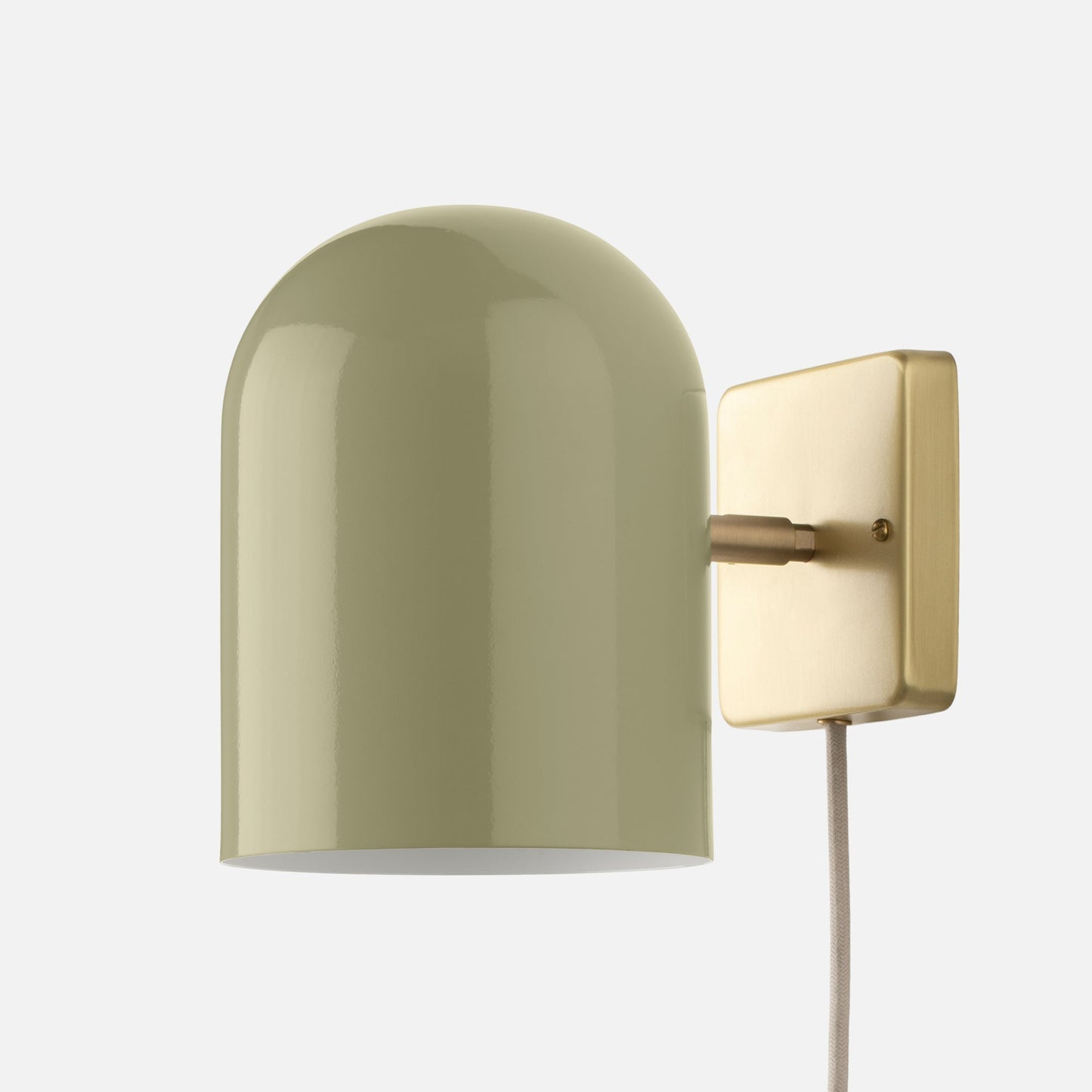 Close-up of Allegheny six-inch plug-in sconce showing sage green cylindrical shade and brushed brass wall plate on white background