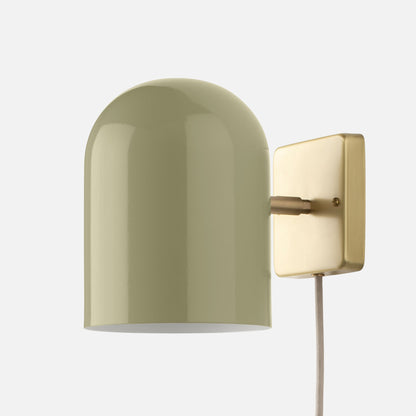 Close-up of Allegheny six-inch plug-in sconce showing sage green cylindrical shade and brushed brass wall plate on white background