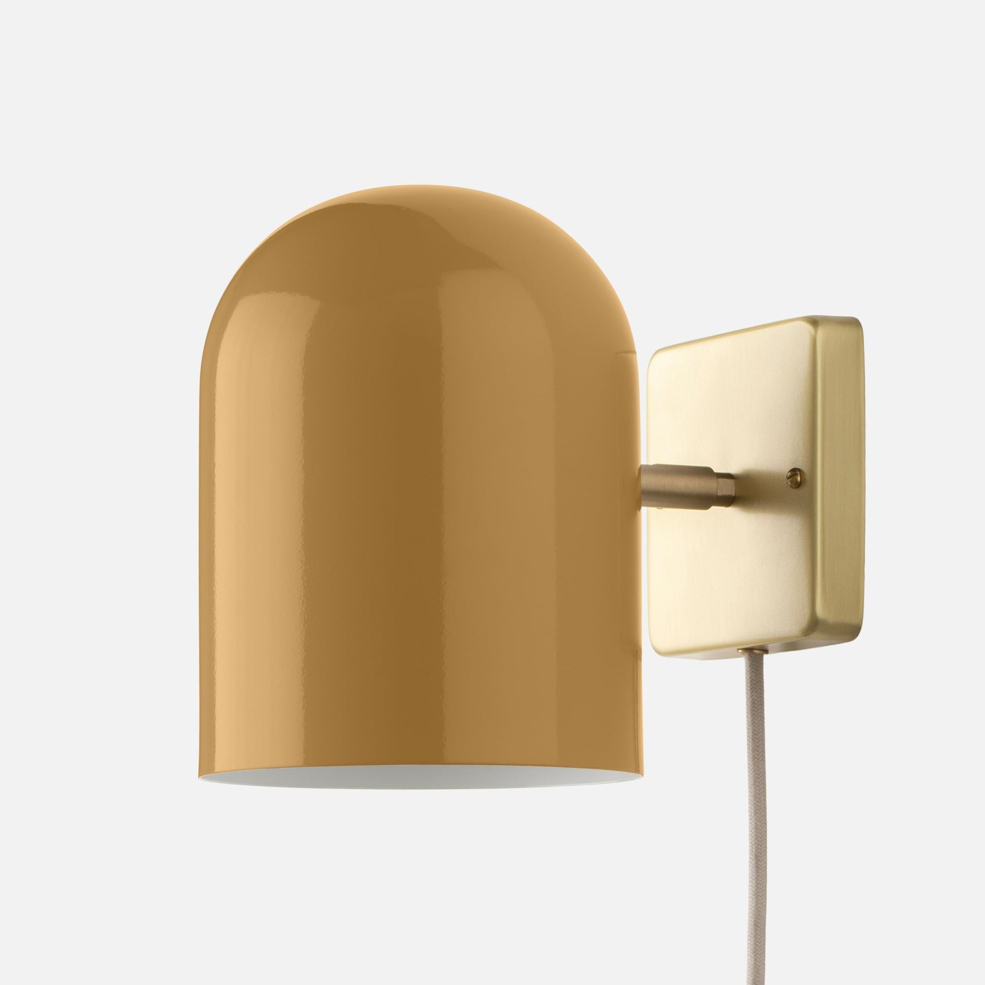Close-up of Allegheny 6-inch Plug-In Sconce showing glossy mustard yellow metal shade and brass wall plate on white background
