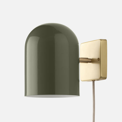 Close-up of Allegheny 6-inch plug-in sconce showcasing olive green dome shade and brushed brass backplate on white background
