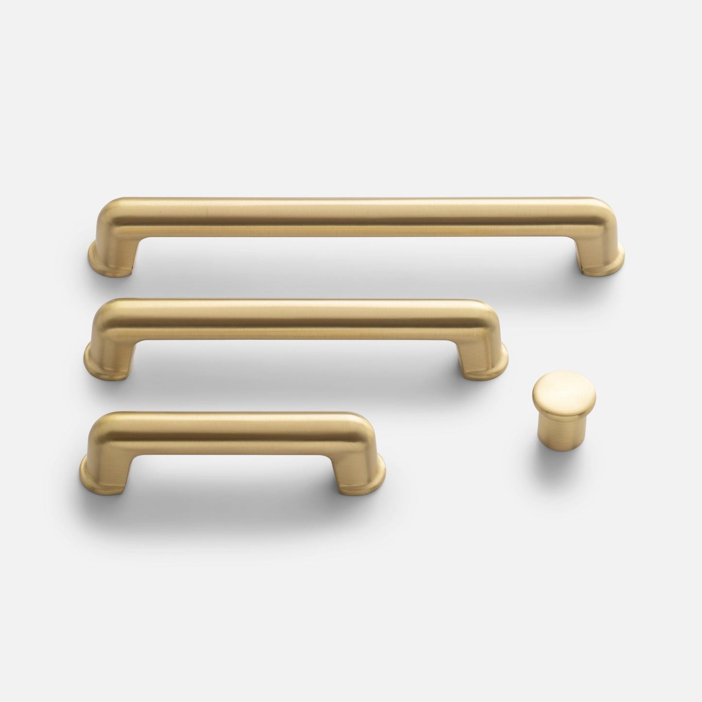Top-down view of Remy pulls and matching knob showcasing rounded corners and satin brass finish on light gray background