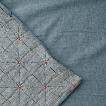 Close-up of Peak Stitch Duvet showcasing triangular matelassé quilting and red stitch ties on blue cotton twill reverse