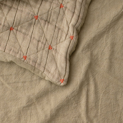 Close-up of Peak Stitch Duvet showing triangular matelasse quilting and red yarn-tie stitches on beige cotton twill