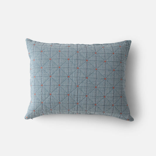 Top view of Peak Stitch sham showing blue quilted fabric with diamond grid and small red embroidered crosses on white background